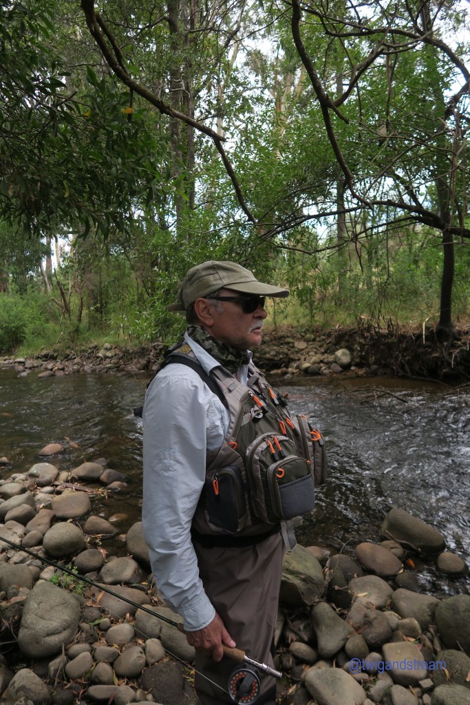 Man in fly fishing attire next to river